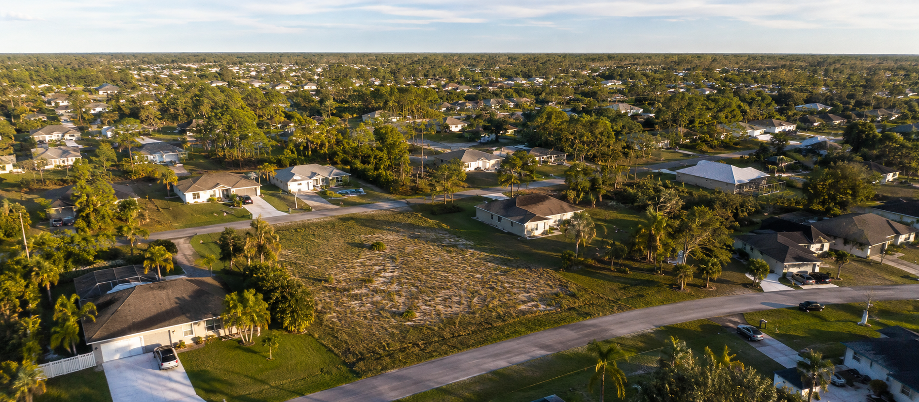 Palm Bay neighborhood with a vacant residential infill parcel in warm late-afternoon light